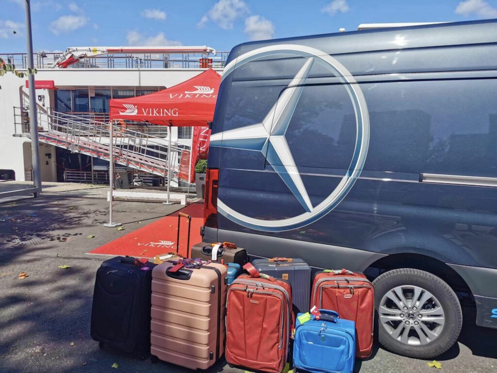 Valises devant un camion Smart Transports, photo prise face à un bateau de croisière pendant un transport de bagages