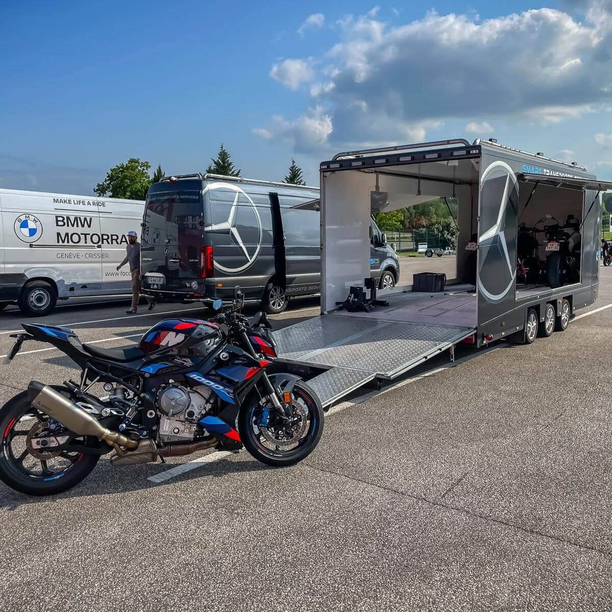 Remorque sur un parking prête à recevoir une moto, positionnée devant la rampe